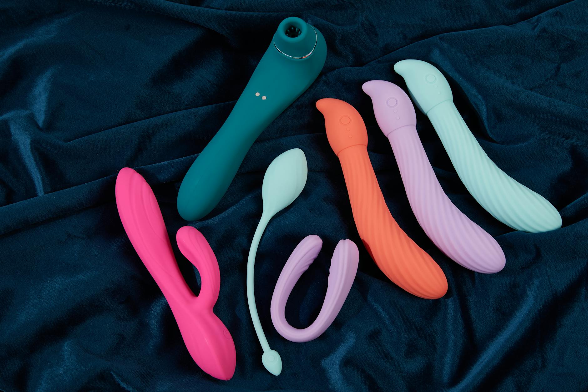 Colorful vibrators arranged on a bright yellow surface, representing joy and self-care