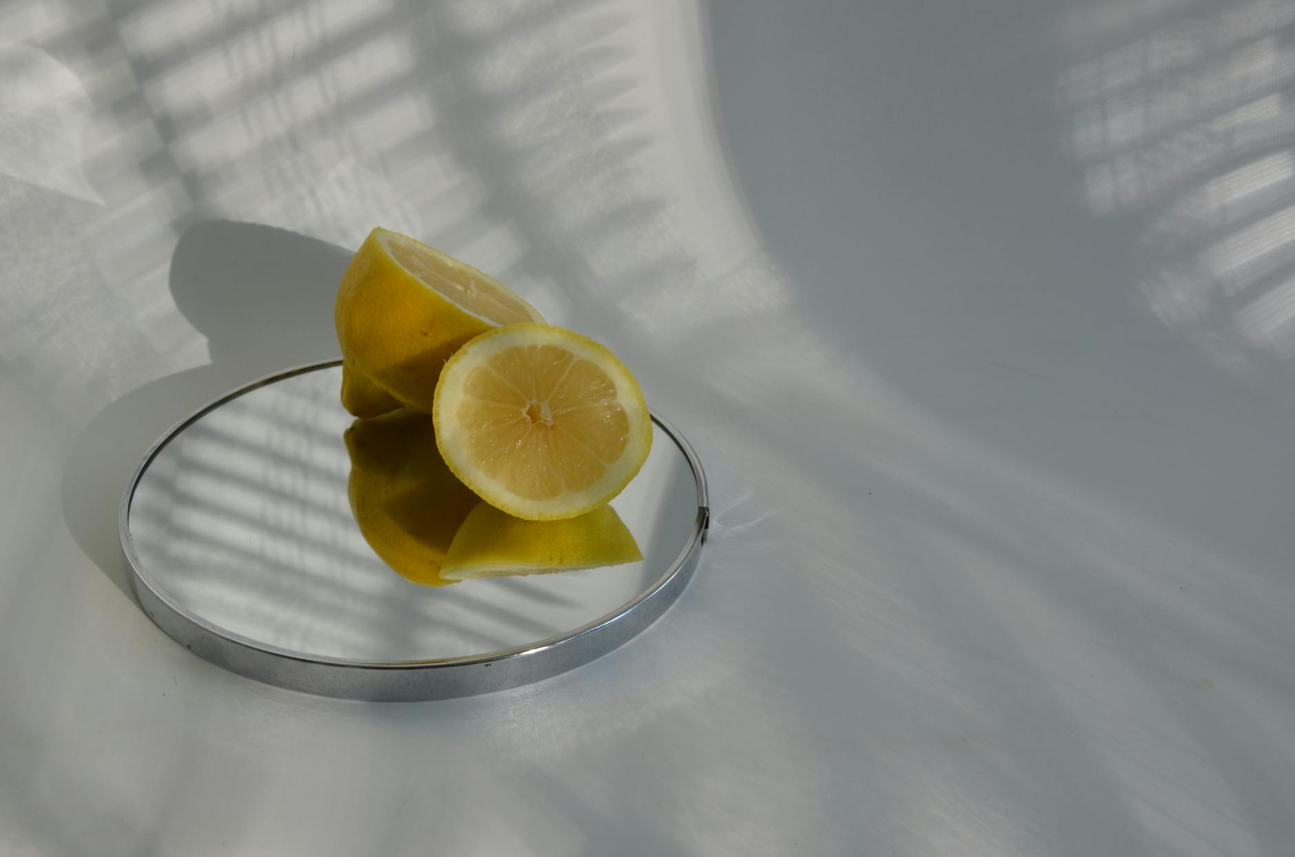 Hand holding a fresh lemon on soft pink background with additional lemons nearby