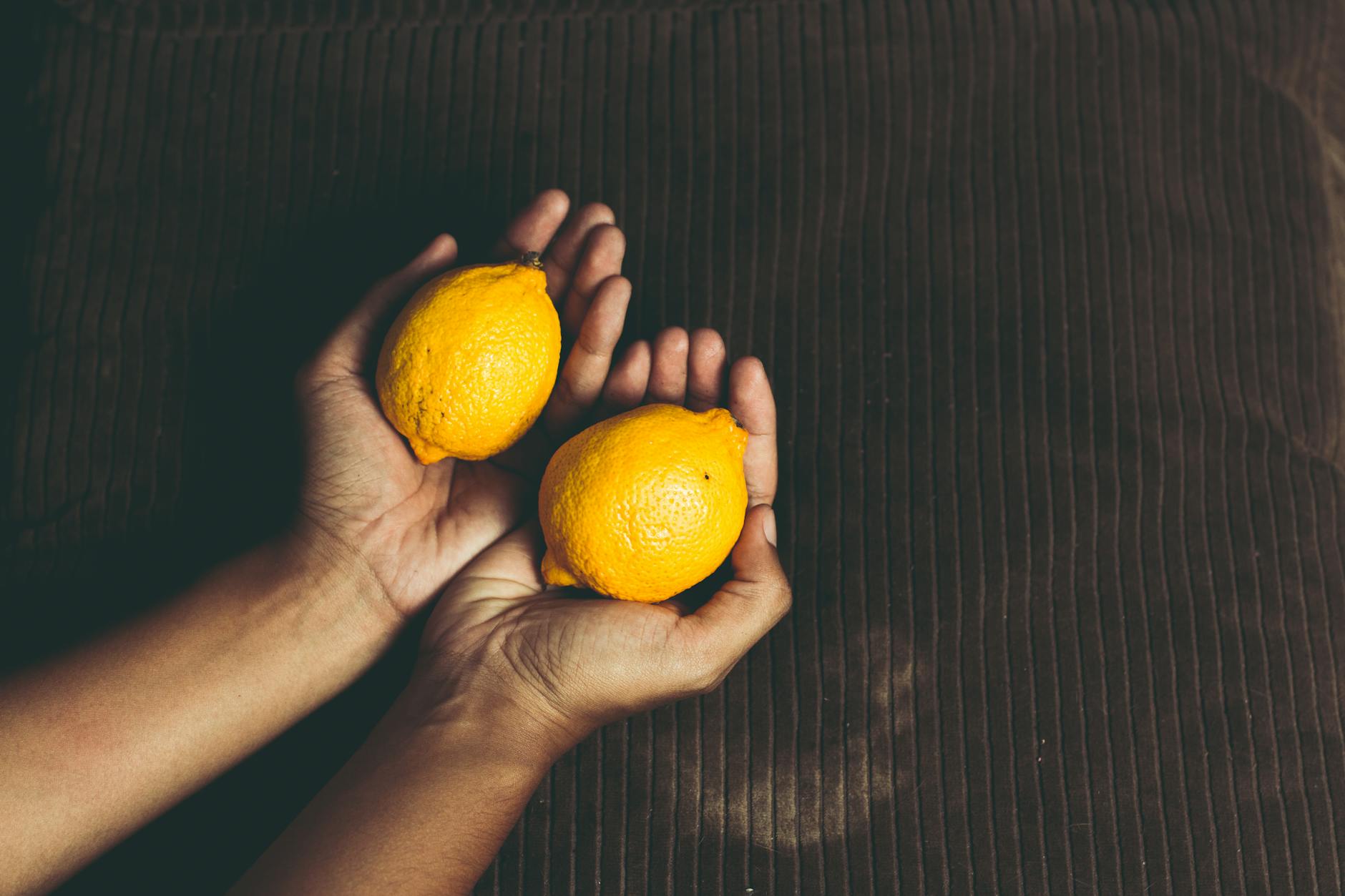 Two fresh lemons held in cupped hands, symbolizing rekindled pleasure and natural restoration.