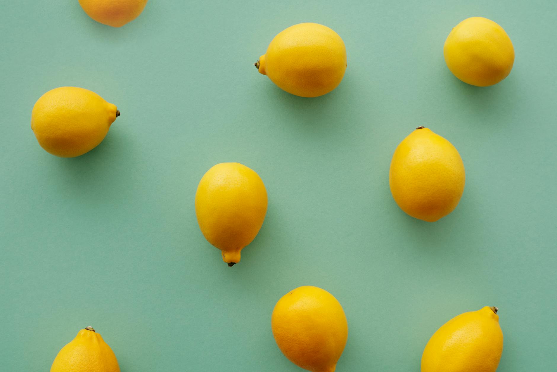 Hand holding a fresh lemon against a vibrant yellow background, symbolizing the bright, modern approach of lemon clitoral stimulation.