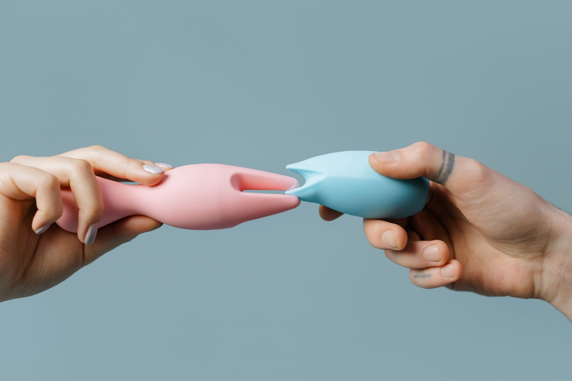 Close-up of a hand holding an orange vibrator against a purple backdrop, showcasing modern sensuality and touch