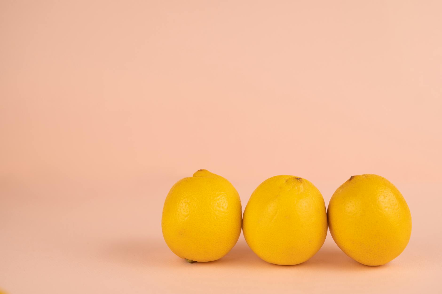Bright yellow lemons arranged on a soft pastel background